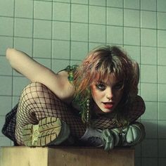 a woman in fishnet stockings laying on top of a wooden box next to a tiled wall