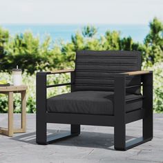 a black chair sitting on top of a stone floor next to a table with a cup