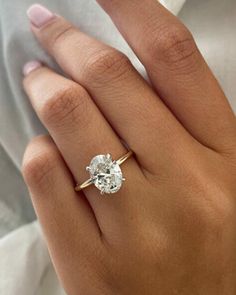 a woman's hand with a diamond ring on top of her finger and an engagement band