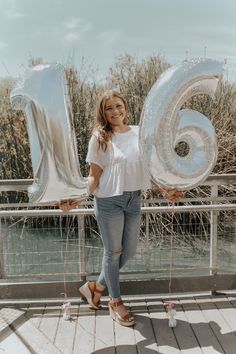 a woman standing in front of the number six balloon