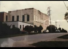 an old building with cars parked on the side of the road in front of it