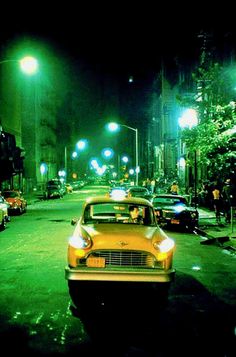 a yellow taxi cab parked on the side of a street at night