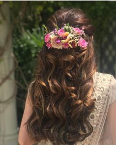 the back of a woman's head with flowers in her hair, wearing a white dress