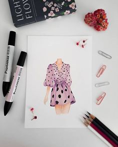 a drawing of a woman's dress on top of a table with markers and pens