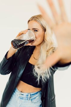 a woman in black jacket drinking from a bottle