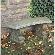 a stone bench sitting on top of a lush green field next to a hedge covered in leaves