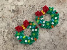 two pairs of earrings made out of legos sitting on top of a stone surface