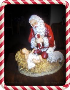 a statue of santa claus holding a baby jesus on top of a pile of hay