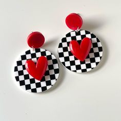 a pair of heart shaped earrings on top of a checkered tablecloth pattern plate