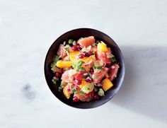 a black bowl filled with fruit salad on top of a white counter