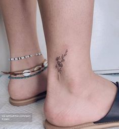 a woman's foot with a small flower tattoo on the left side of her ankle