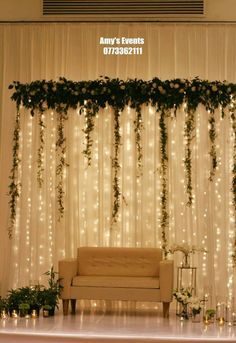 a couch sitting in front of a white curtain covered wall with greenery on it