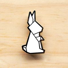 a white and black lapel pin with an origami rabbit on it's back