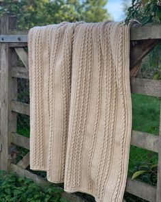 two knitted blankets hanging on a wooden fence