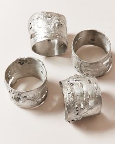 four silver rings sitting on top of a white table