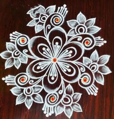 an intricate design on a wooden surface with white paint and red dots in the center