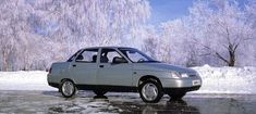 a silver car parked on top of a ice covered road next to trees and bushes