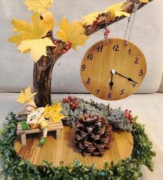 a wooden clock sitting on top of a table next to a pine cone and some leaves