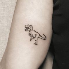 a small dinosaur tattoo on the arm