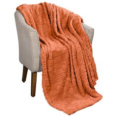 an orange blanket sitting on top of a chair next to a wooden legrest and arm rest