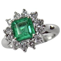 an emerald and diamond ring on a white background