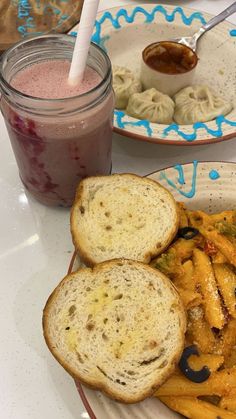 two plates with pasta and bread on them next to a jar of jelly shaker