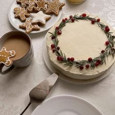 a table topped with plates and cakes covered in frosting next to christmas themed cookies