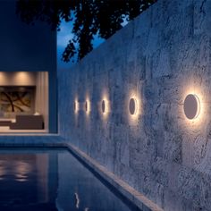 a wall with some lights on it next to a pool