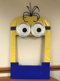 a paper plate cut out of the shape of a minion with googly eyes