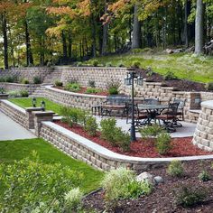 an outdoor patio area with stone walls and seating areas, surrounded by green grass and trees