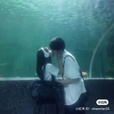 a man and woman kissing in front of an aquarium