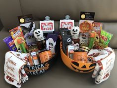 two halloween baskets with candy and treats in them sitting on a couch next to each other