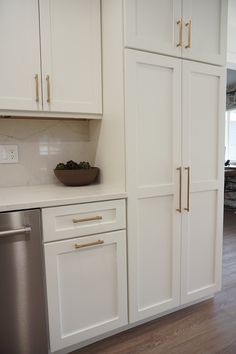 a kitchen with white cabinets and stainless steel dishwasher