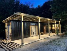 a building made out of shipping containers sitting in the middle of a forest at night