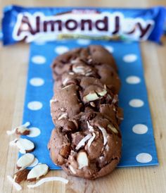 a chocolate cookie with white sprinkles and almonds on a blue napkin