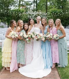 a group of women standing next to each other in front of a white bench with flowers