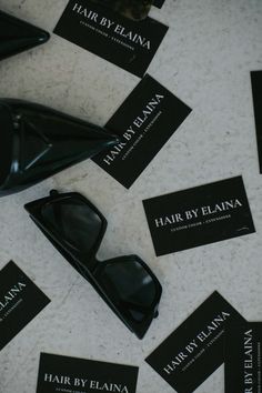 there are many business cards on the floor next to some black shoes and one has a pair of sunglasses