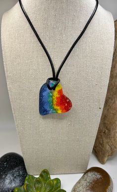 "Show your ❤️ with this chunky rainbow heart pendant. Handmade fused glass heart in rainbow colors with a hint of dichroic glass for that extra sparkle. Measures approx 2\" x 1 3/4\" with an approx 18\" leather cord. Gold tone lobster claw clasp." Rainbow Necklace With Heart Charm As Gift, Trendy Rainbow Heart-shaped Jewelry, Personalized Heart-shaped Rainbow Jewelry, Heart-shaped Rainbow Necklace For Gift, Adjustable Heart-shaped Multicolor Necklaces, Pride Jewellery, Rainbow Necklace, Rainbow Heart, Glass Heart