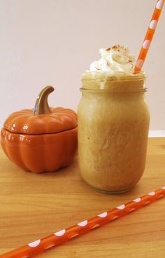 a pumpkin smoothie in a mason jar next to an orange and white striped straw