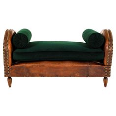 a green velvet and leather chaise lounger with studded wooden legs on an isolated white background