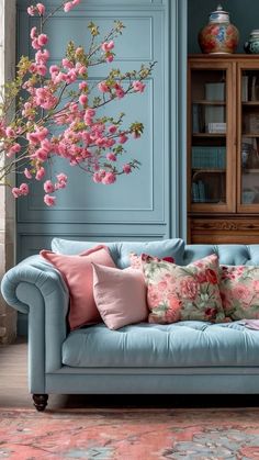 a living room with blue walls and pink flowers on the couch