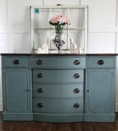 a blue dresser with flowers in a vase on top