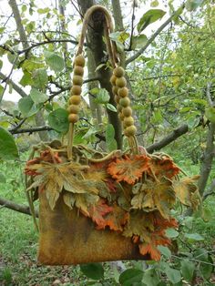 an old purse hanging from a tree in the woods with leaves and berries on it