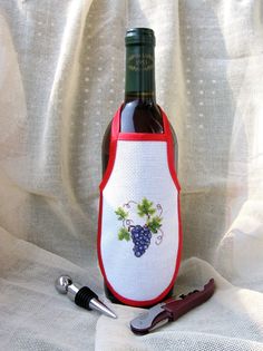 a wine bottle with a red and white apron on it next to a pair of scissors