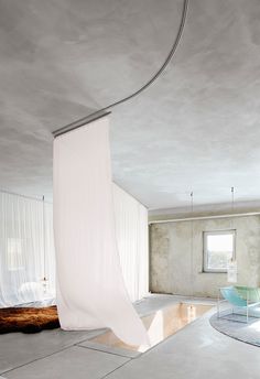 an empty room with white drapes hanging from the ceiling and a bed in the corner