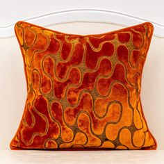 an orange and red pillow on a white chair