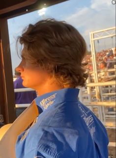 a woman wearing a blue shirt is looking out the window at an arena full of people