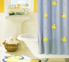 a bathroom with yellow rubber ducks on the shower curtain and blue rugs in front of the tub