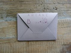 an envelope with the word ariane written on it is sitting on a wooden surface