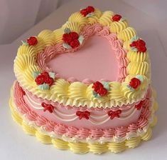 a heart shaped cake with frosting and flowers on it's sides, sitting on a white surface